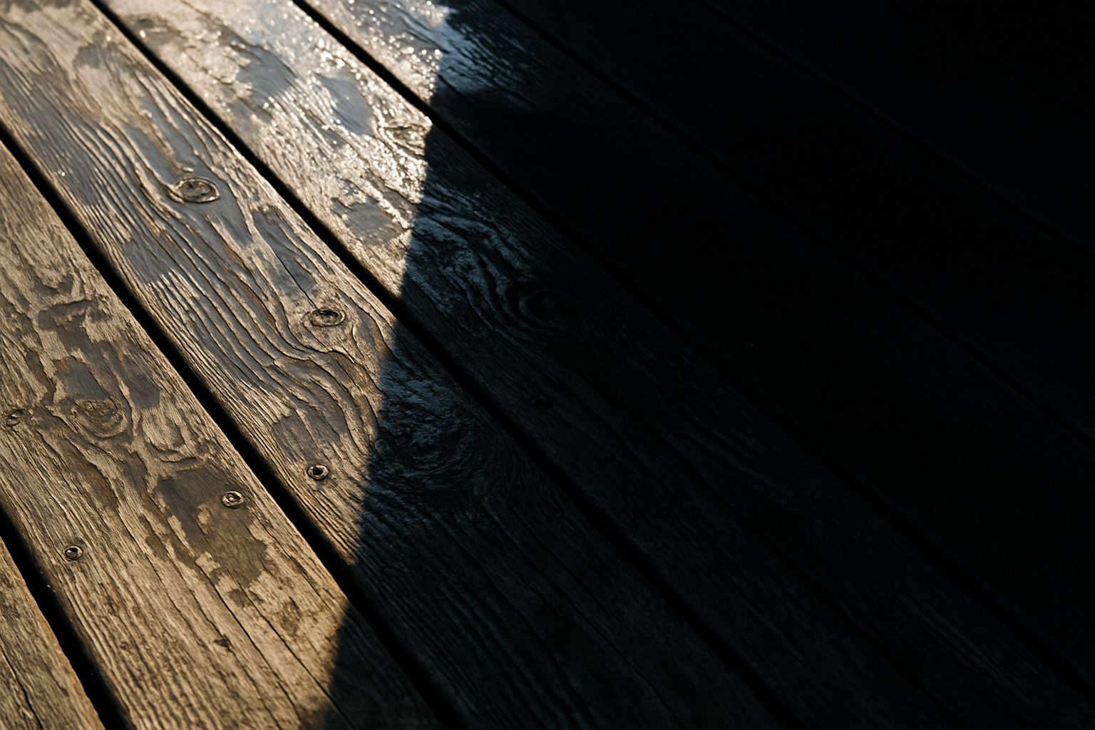A hard shadow across a wet deck. Everything is decided by what is in the way before the light arrives.